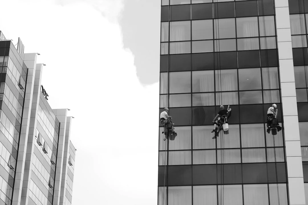 A man cleaning skyscraper windows with a harness, showcasing urban high-rise work.